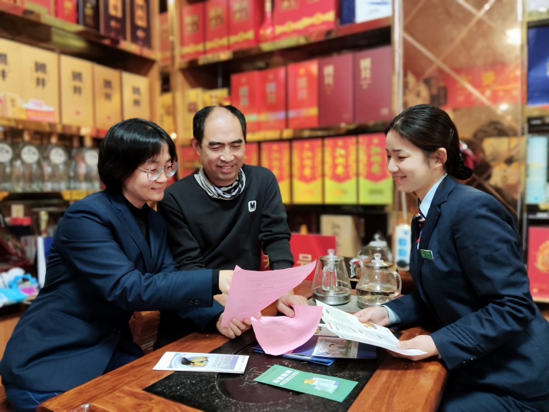 图为烟草、邮政工作人员向零售户介绍助农惠农政策